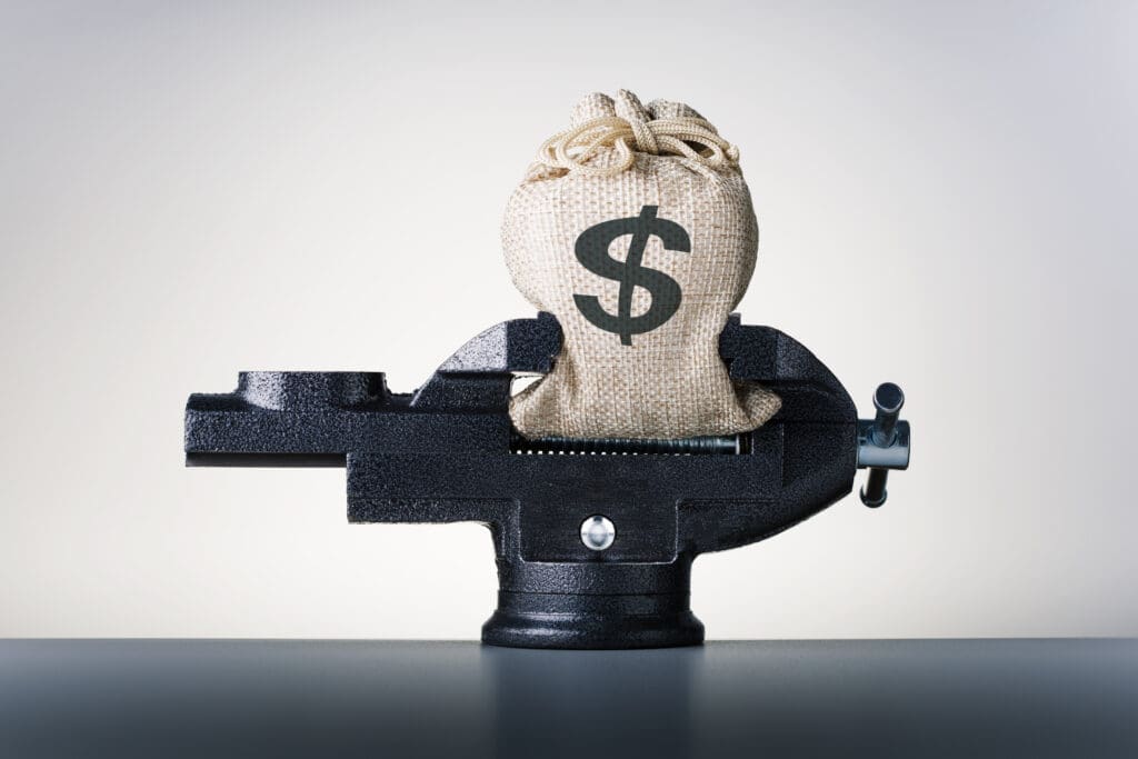 Crisis. Concept of reducing costs. Bag with dollars money in vise.