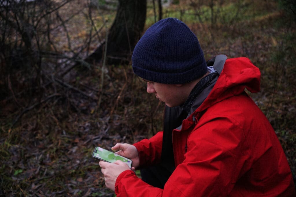 a man is looking at a navigation device on his phone. Hiking navigation, online maps