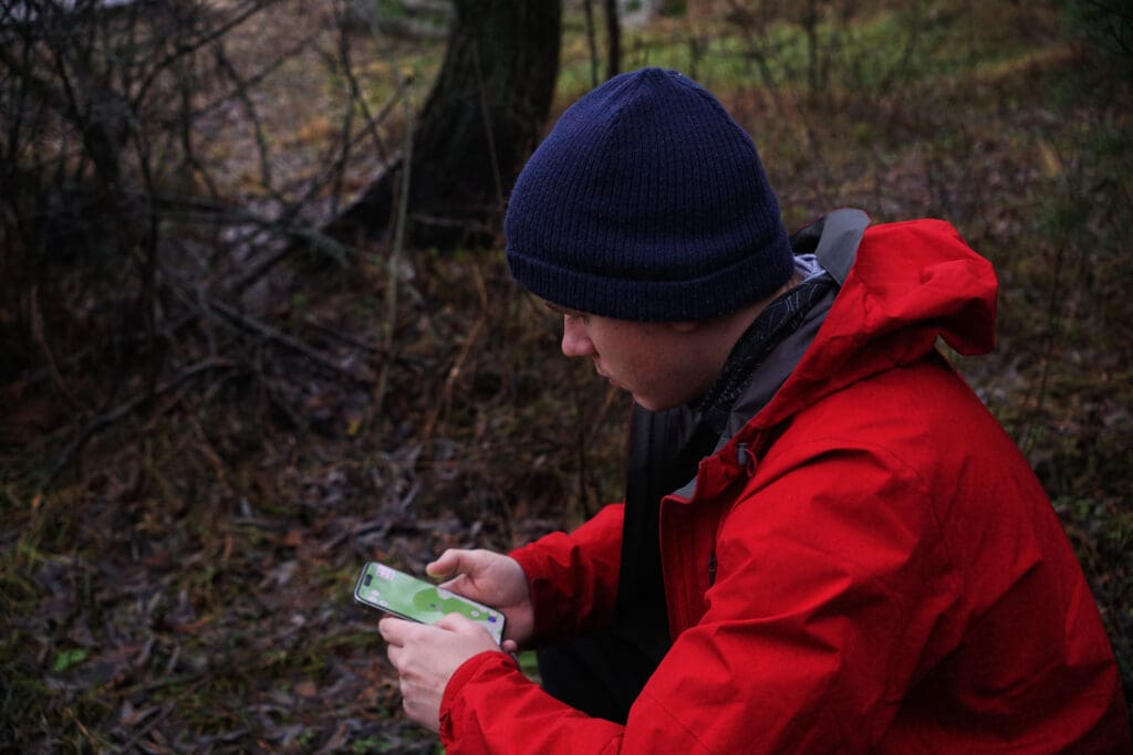 a man is looking at a navigation device on his phone. Hiking navigation, online maps